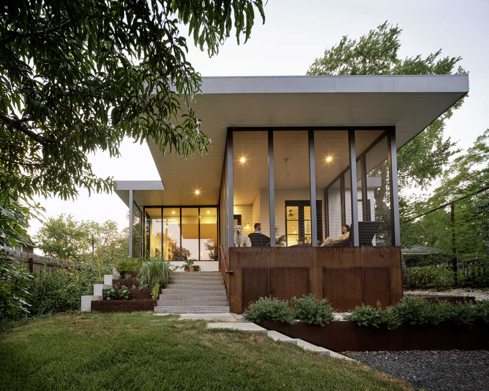 A contemporary house featuring glass walls and a spacious deck.