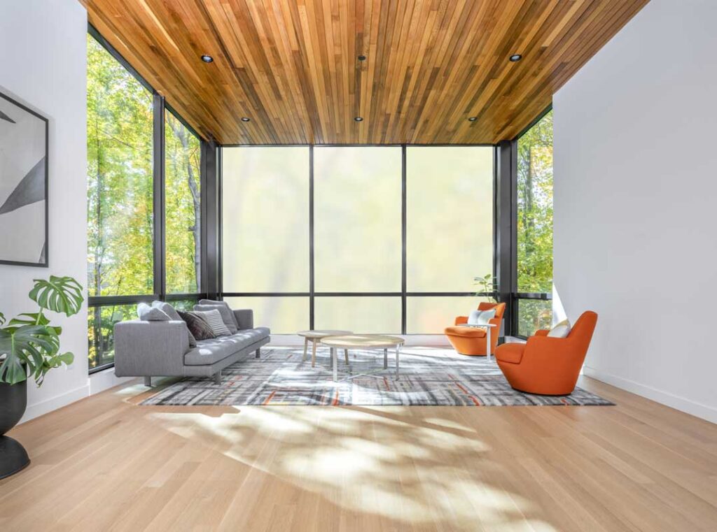 A contemporary living room with wooden ceilings and expansive windows, offering ample natural light.